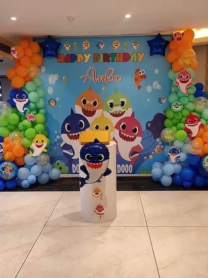 An immersive Baby Shark themed birthday party. This large-scale decoration includes a full-size printed backdrop with all the characters, organic balloon garlands in ocean colors, and a custom cake stand to complete the underwater adventure.