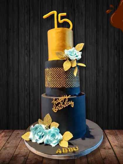A grand 75th birthday calls for a grand cake. This three-tier design in black and gold with delicate blue sugar flowers was created for a client's "Abbu," offering a sophisticated and memorable centerpiece for the celebration.