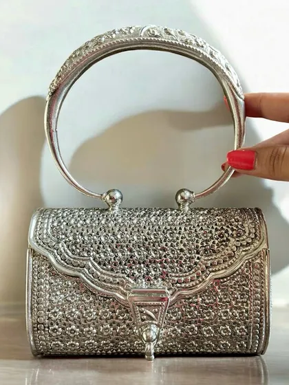 For a bold statement, a silver clutch is a must. This piece features incredibly detailed filigree work across its entire surface and a rigid, carved handle, making it a masterpiece of silver craftsmanship.