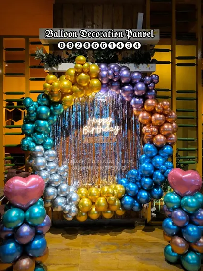 A vibrant, multi-color chrome balloon ring backdrop for a birthday party in a restaurant or hall.
