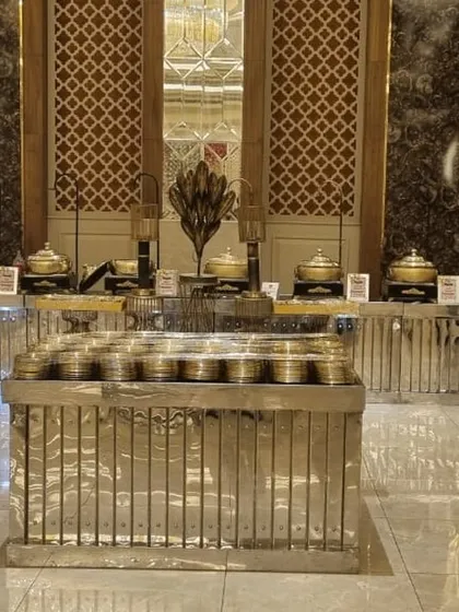 An elegant and symmetrical buffet arrangement in a grand hall with ornate walls. The silver-colored counters and traditional serving bowls create a look of classic sophistication.