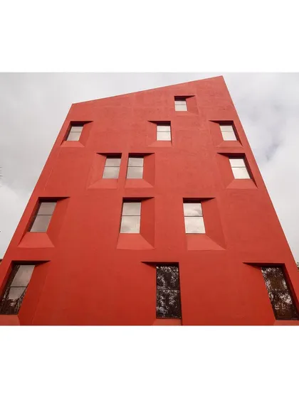 A worm's-eye view of the "Stacked Student Housing" facade emphasizes its sculptural quality. The splayed window openings are not random but are carefully placed to correspond with the split-level interior spaces.