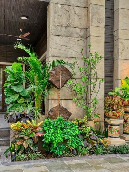 The entrance to a home should make a statement. We designed this corner with a mix of lush tropical plants, mosaic-detailed planters on pedestals, and a unique stone sculpture to create a grand and green welcome.