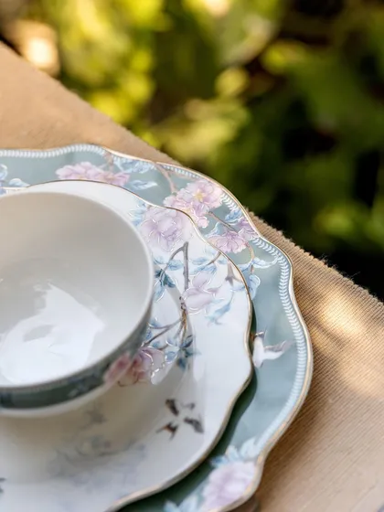 A close-up, artistic shot of Vigneto's floral-patterned plates. The shallow depth of field creates a soft, dreamy look, focusing the eye on the delicate details of the crockery's design.