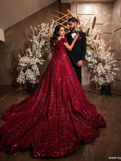 A dramatic, full-length portrait showcasing the bride's magnificent red reception gown. This is a true statement photograph.