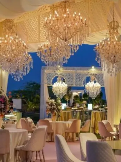An elegant evening reception setup under a draped canopy, illuminated by dozens of magnificent crystal chandeliers. The pastel color scheme and sophisticated table settings create a luxurious and timeless atmosphere for a large gathering.