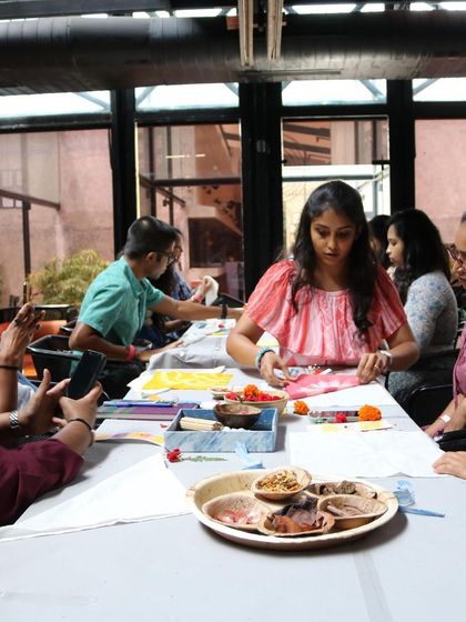 A wide shot of the workshop in session. Everyone is focused on folding and tying their napkins, getting them ready for the dye pot.