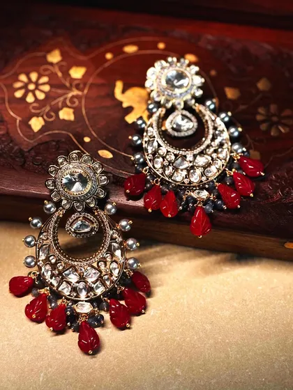Bold and beautiful. These chandbali earrings are crafted with large polki stones and vibrant red drops, designed to make a statement.