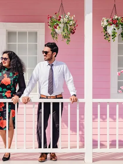 The couple enjoys a moment on the porch of a charming pink house. This relaxed and stylish shot captures a slice-of-life feel, making their pre-wedding photos feel personal and unique.
