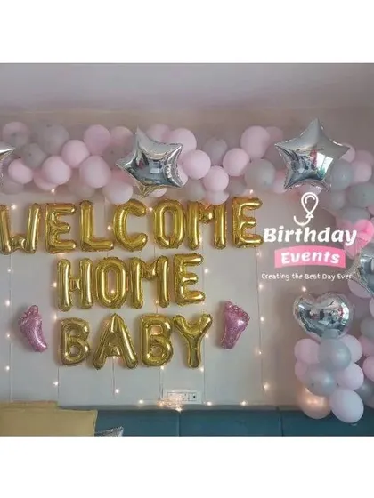 A classic 'Welcome Home Baby' wall decoration. This arrangement uses gold foil letter balloons, a pink and grey balloon garland, and silver star accents to create a lovely photo corner in your home.