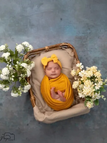 A full view of the newborn in a basket, surrounded by white flowers. The yellow and white color scheme is fresh and cheerful.