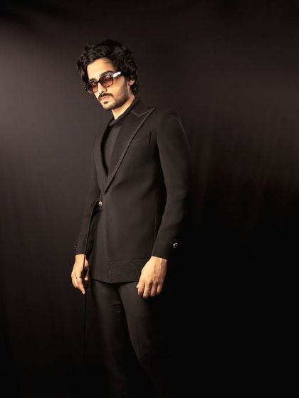 This all-black ensemble features an asymmetric jacket with a subtle glitter detail on the lapel. It's a modern, edgy take on formal wear, designed for making an entrance.