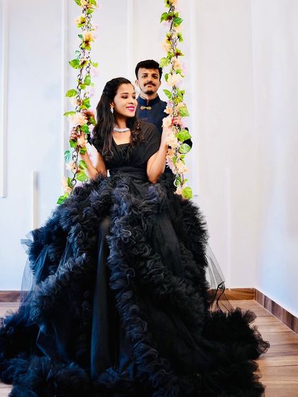 A glamorous pre-wedding shot featuring our black ruffled gown. The floral swing adds a touch of whimsy and romance to this elegant couple portrait.