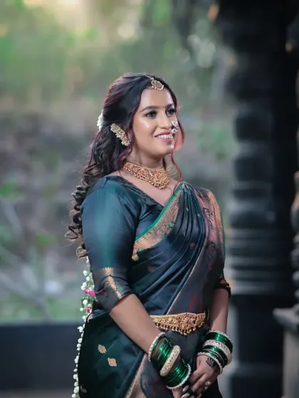 A beautiful candid shot of a bride in a dark green traditional saree. The soft, wavy hair and glowing makeup create a romantic and timeless feel.