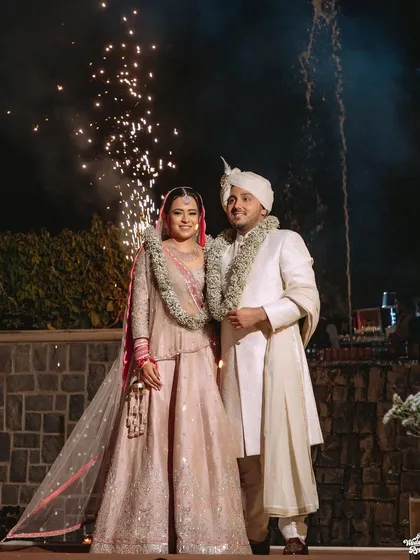 A classic portrait of the couple with sparklers in the background, celebrating their union at their Delhi wedding.