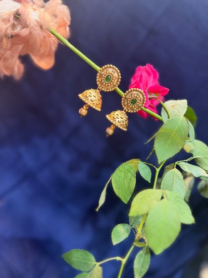 A pair of classic gold jhumkas with green stones. This timeless design can be paired with almost any traditional suit or saree.