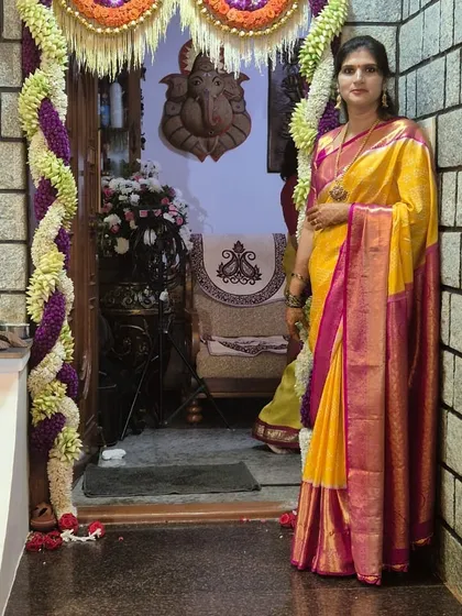 Vedha standing in a beautifully decorated doorway, her festive saree a perfect match for the occasion.