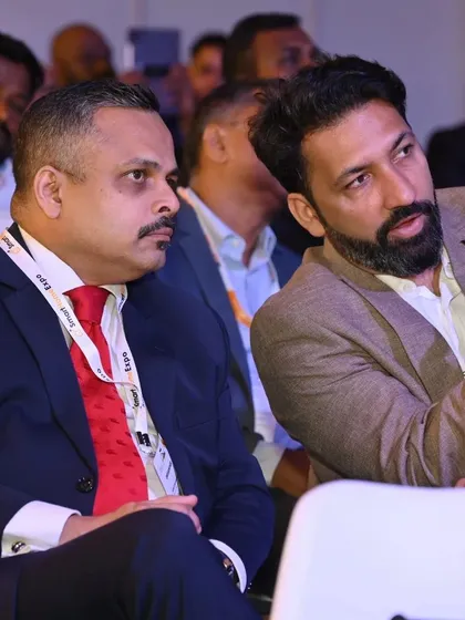 A focused discussion between two professionals during a conference, illustrating the opportunities for peer-to-peer knowledge sharing.