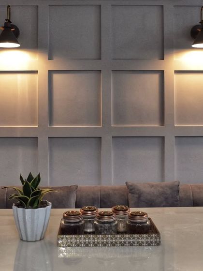 This dining nook features a comfortable built-in bench against a classic wainscoting wall, lit by industrial-style sconces for a cozy, cafe-like feel.