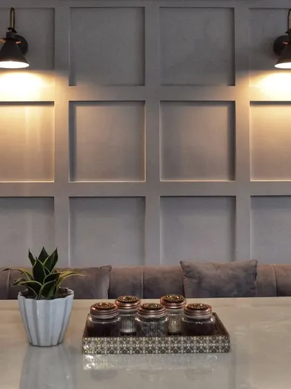This dining nook features a comfortable built-in bench against a classic wainscoting wall, lit by industrial-style sconces for a cozy, cafe-like feel.