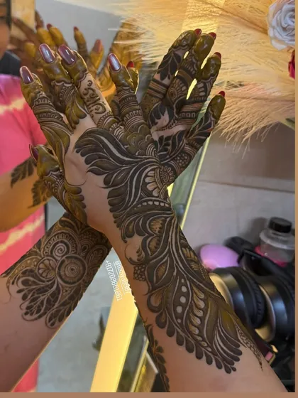 A dynamic pose showcasing the flow of this intricate henna design. The pattern wraps around the hands and arms, creating a sense of movement.
