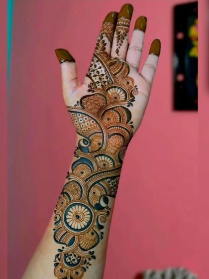 This is a classic Arabic-style 'bel' or vine design. It flows diagonally across the hand, featuring bold outlines and shaded floral and paisley elements.