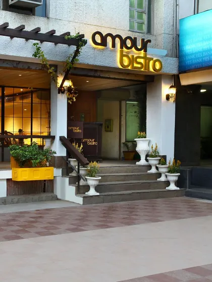 The facade of Amour Bistro in New Delhi creates a charming, European-inspired street presence. The design offers a tranquil, native ambiance amidst the city's chaos, inviting passersby into its warm and elegant interior.
