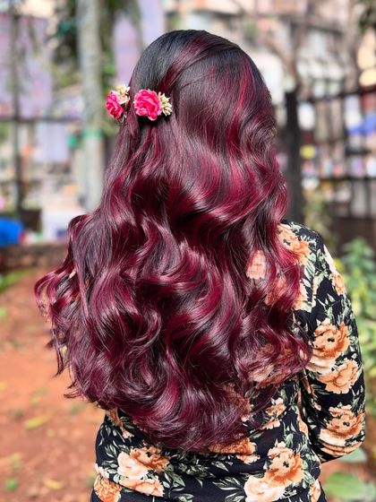 We're obsessed with this wine red hair color. Accessorized with flowers, this look is romantic, bold, and absolutely beautiful.