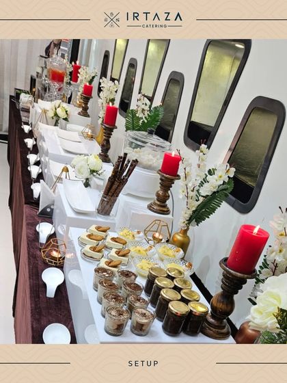 A long view of a dessert and appetizer table for a home party. The setup uses wooden risers and elegant candles to create a beautiful display in a compact space.
