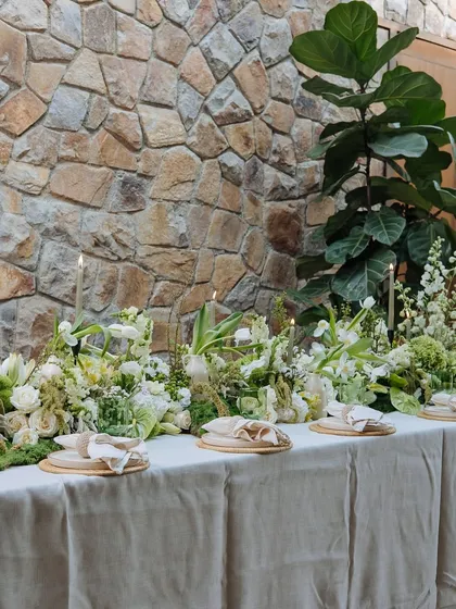 The full length of the Earth Table is set for an intimate dinner. The arrangement of plates, candles, and florals creates a rhythm that is both elegant and organic.