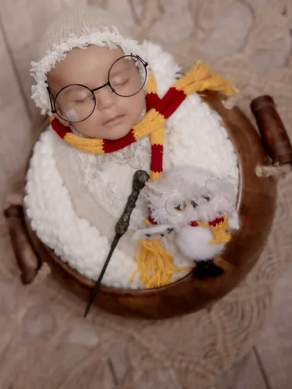 Welcome to the wizarding world, little one. This creative Harry Potter themed newborn shoot features a sleeping baby with iconic glasses, a Gryffindor scarf, and a magic wand, showing how we bring your favorite stories to life.