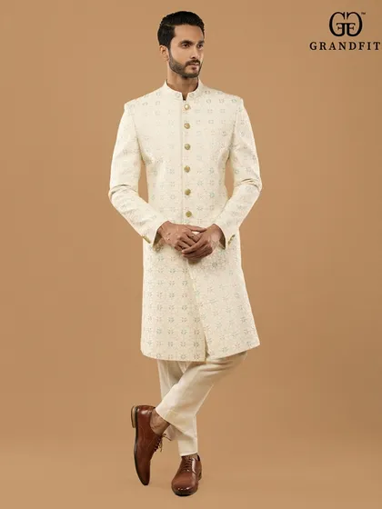 Understated elegance defined. This custom-made ivory sherwani showcases subtle, all-over embroidery on premium fabric, offering a timeless and sophisticated look for any celebration.