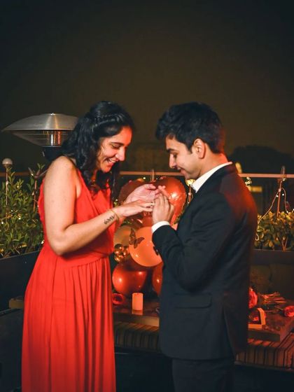 A candid moment during a rooftop proposal, as the ring is being placed on her finger.