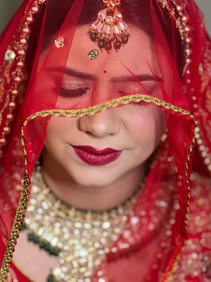 A beautiful shot of the bride under her red veil. The focus is on her flawless skin and the deep red lip color.