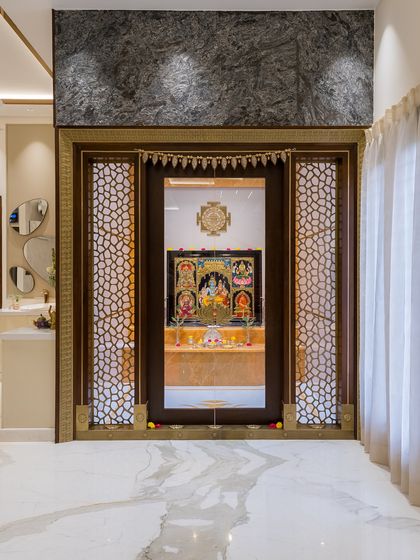 A doorway to devotion. This traditional mandir features ornate brass jaali screens, a dark wood frame, and a beautifully lit interior, creating a grand and sacred spiritual centerpiece in the home.