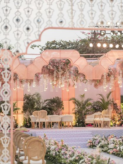 A view through the intricate jali archway towards the main mandap. This layered perspective highlights the depth and detail of the overall wedding design.