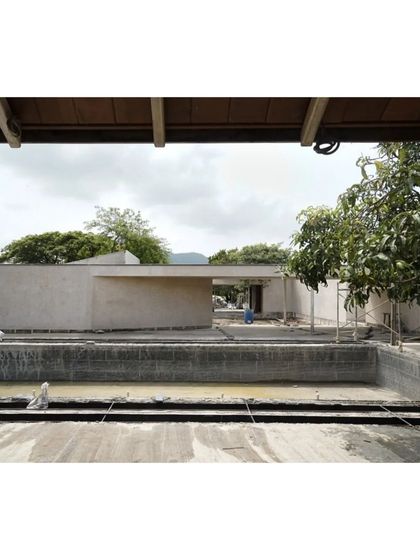 A view across the empty pool towards the main house during construction in Alibaug. The building's simple, clean lines are already apparent.
