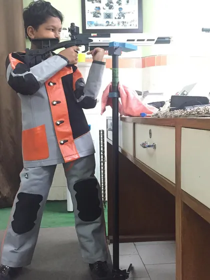 A very young shooter learning the basics of rifle shooting with a stand for support. We welcome all ages.