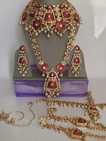 A complete red Meenakari bridal set, including a choker, long necklace, hathphool, nath, and earrings. This is a full rental package for the traditional bride.