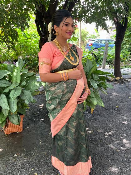A full-length view of Roja's Seemantham look in a beautiful garden setting.