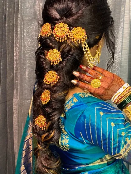 A stunning messy braid for a reception look, adorned with traditional South Indian temple jewelry hair clips. This adds a touch of royalty to the hairstyle.
