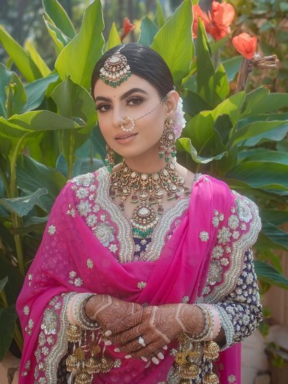 A radiant Sikh bride in an outdoor setting. The neat bridal bun I styled for her keeps the focus on her beautiful features and stunning bridal attire, while ensuring her headwear remains perfectly in place.