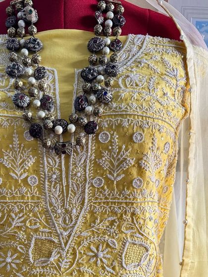 A close-up of the neckline, styled with a traditional necklace.