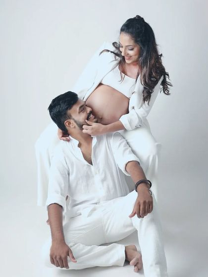 A playful and loving interaction captured in the studio. The all white outfits keep the look clean and modern, while their smiles light up the frame.
