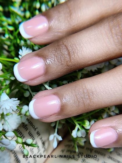 A close-up of a classic French manicure on short, natural nails. This demonstrates that the elegance of French tips is achievable on any nail length, providing a clean and polished finish.