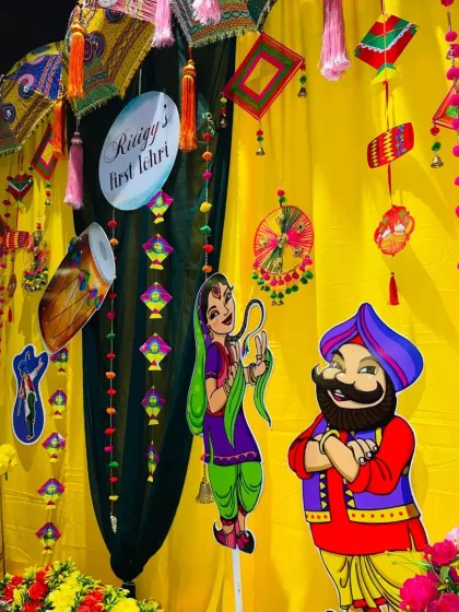 This angle shows the character cutouts of a Punjabi couple and the hanging decorations I used to bring the Lohri theme to life against the dark green and yellow drapes.