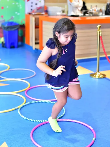 A young girl carefully makes her way through a hula hoop agility ladder. These activities are part of my active camps, designed to be both fun and beneficial for physical development.