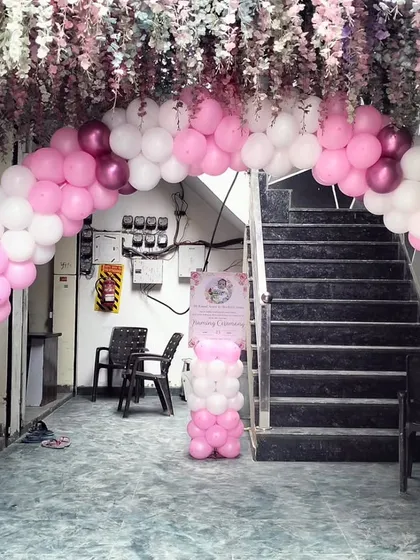 A beautiful entrance for a Naming Ceremony. A pink and white balloon arch is complemented by hanging floral arrangements, creating an elegant and welcoming entryway for guests.