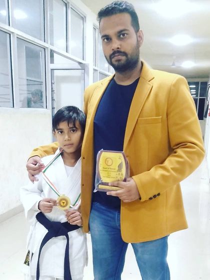 My little brother with his medal and trophy, standing with our coach Satish Kumar. He is a dedicated student and a promising competitor, making our family and dojo proud.