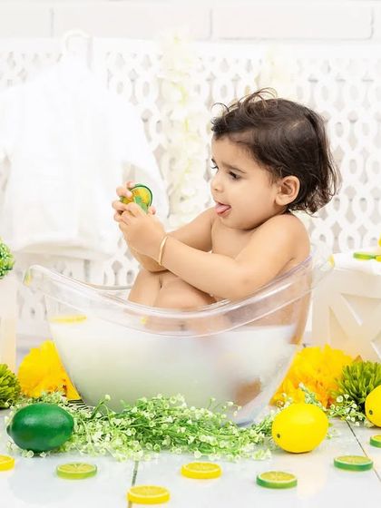 A baby plays with lemon and lime slices in a milk bath, a perfect theme for a fun and sensory photoshoot.